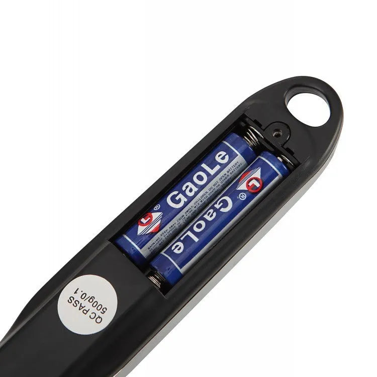 Digital smart measuring spoon with LCD display showing weight reading, on a kitchen countertop