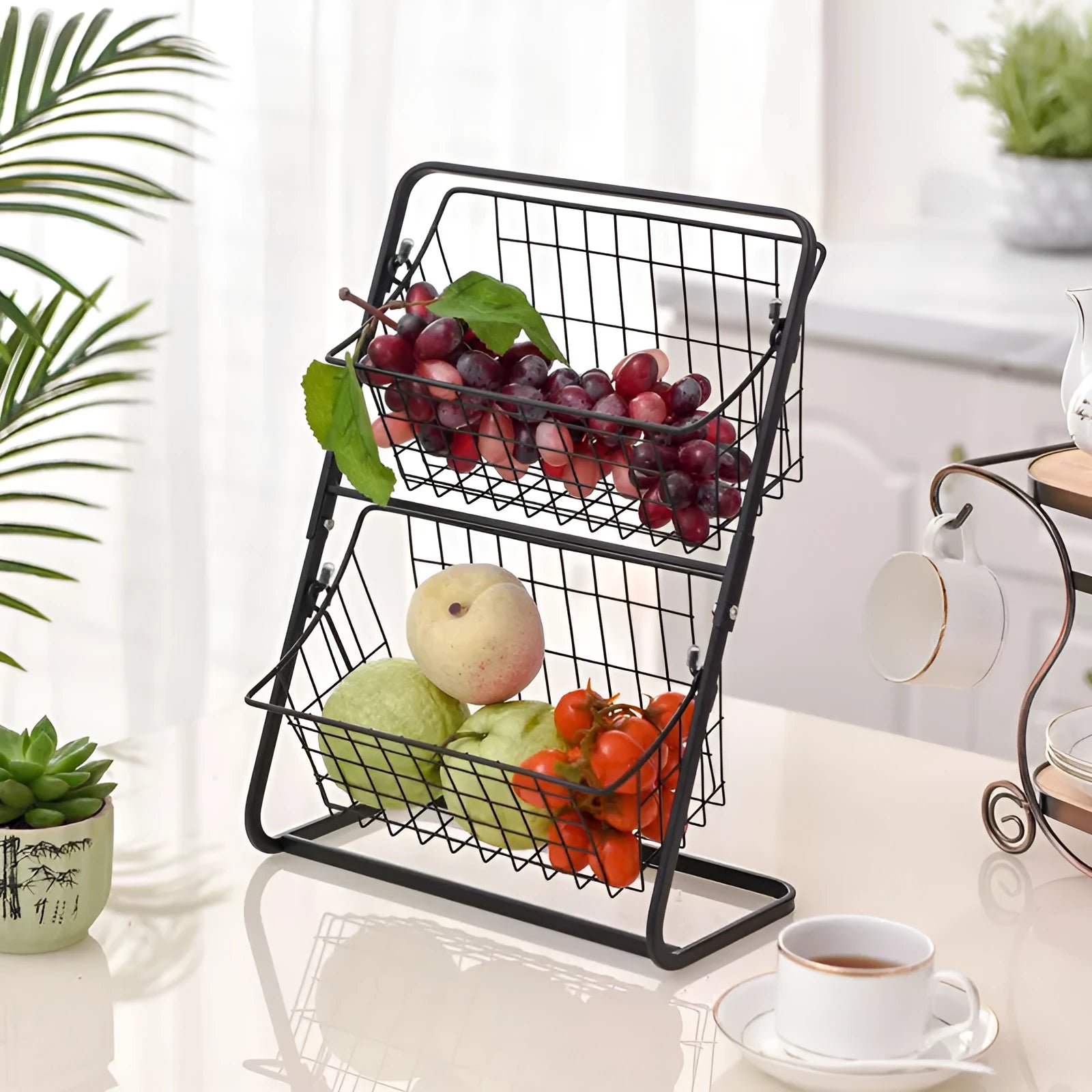 Black two-tier iron art kitchen storage rack with hollowed sides on countertop holding fruit and vegetables
