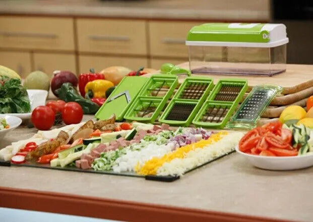Green multifunctional vegetable chopper with handle, grater, and stainless steel blades on a chopping board