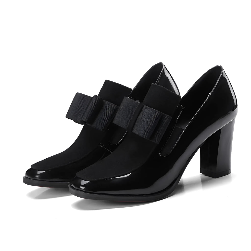 Black patent leather women's high heels with a thick super high heel and square toe on a plain background.
