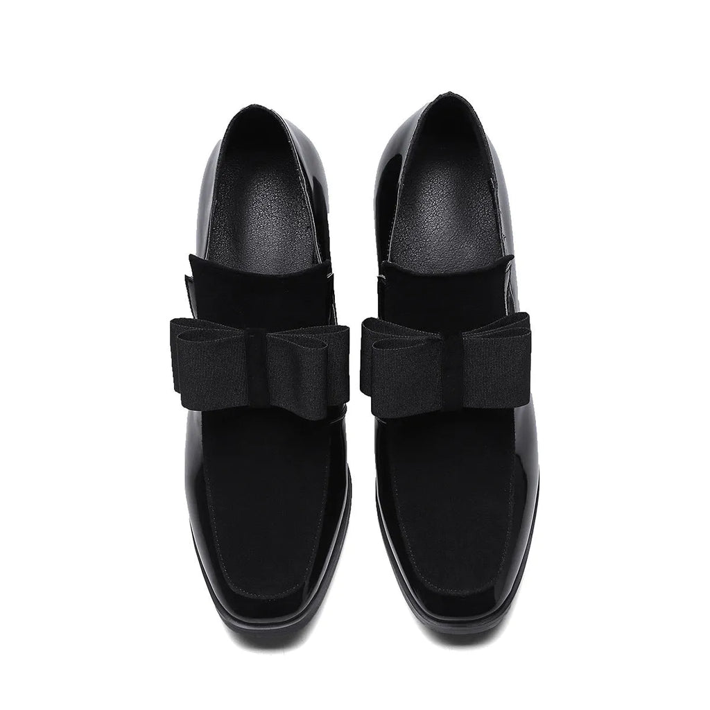 Black patent leather women's high heels with a thick super high heel and square toe on a plain background.
