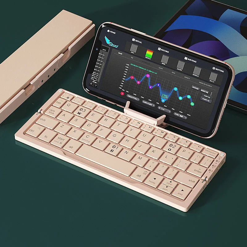 Silver white mini folding Bluetooth keyboard open next to a smartphone on its integrated stand.