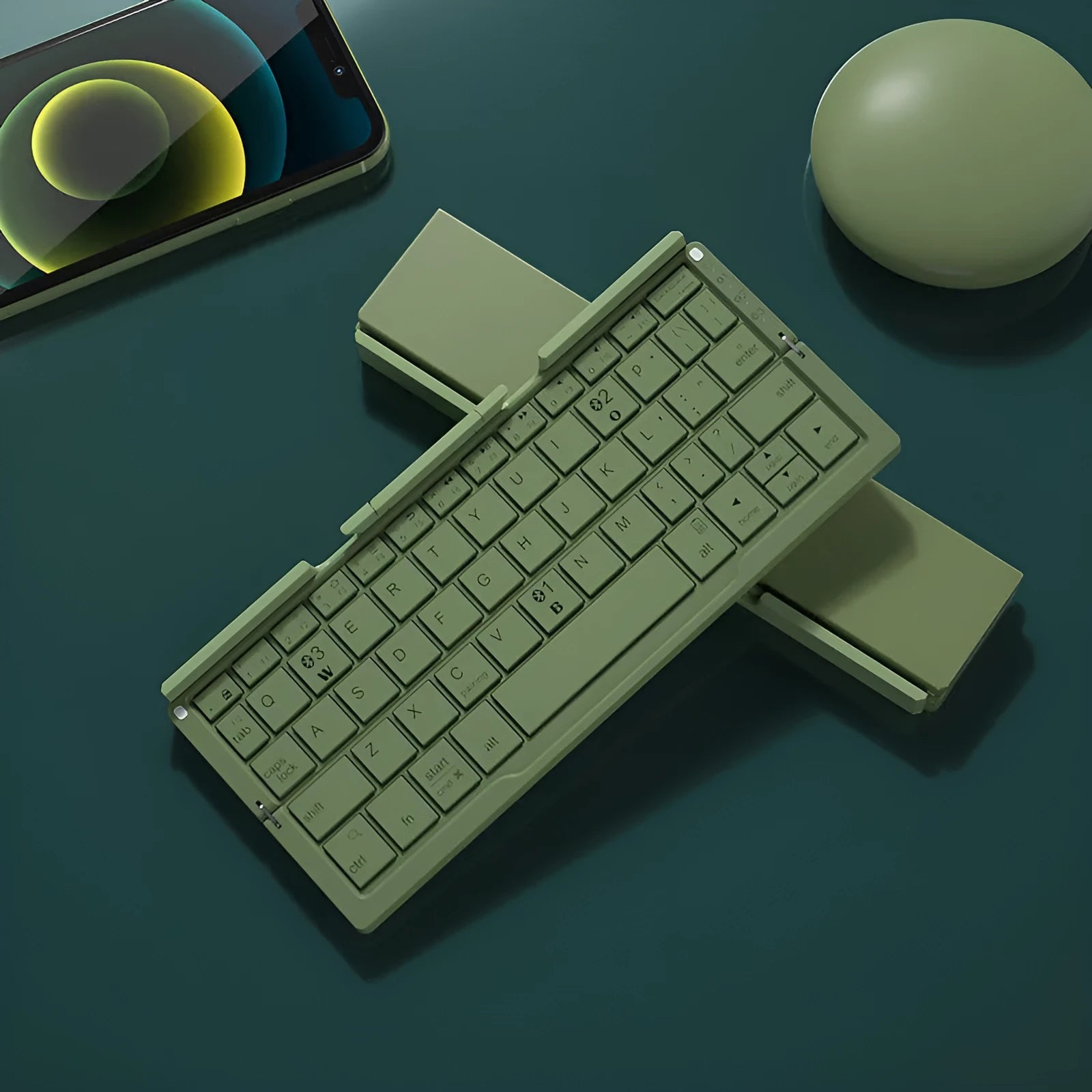 Silver white mini folding Bluetooth keyboard open next to a smartphone on its integrated stand.