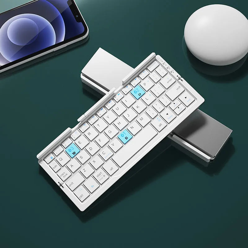 Silver white mini folding Bluetooth keyboard open next to a smartphone on its integrated stand.