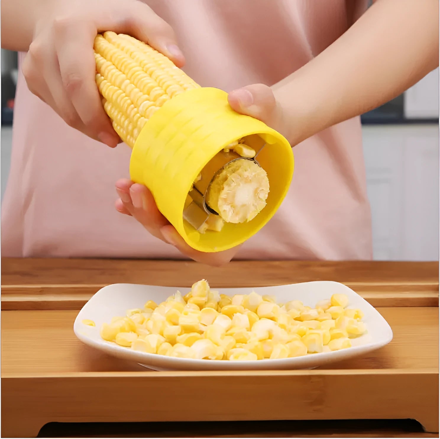 Yellow manual corn grinder thresher with corn-shaped design on a kitchen counter.