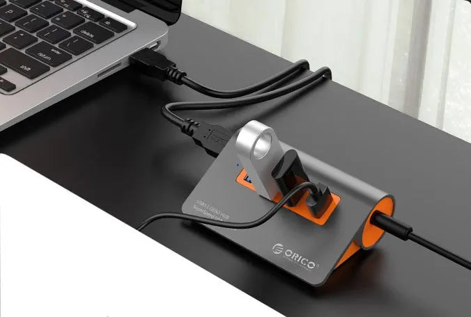 Dark grey aluminium USB hub with four USB 3.1 ports, orange accent, and detachable 100cm cable