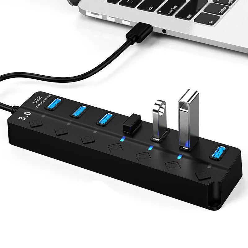 Black 7-port USB 3.0 hub with external power supply on a desktop.