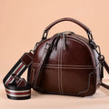 Round leather handbag with zipper closure and soft double handles in wine red colour