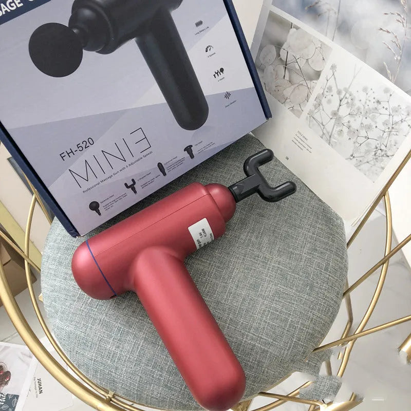 Black handheld electric fascia gun muscle massager with metal head on a grey background.