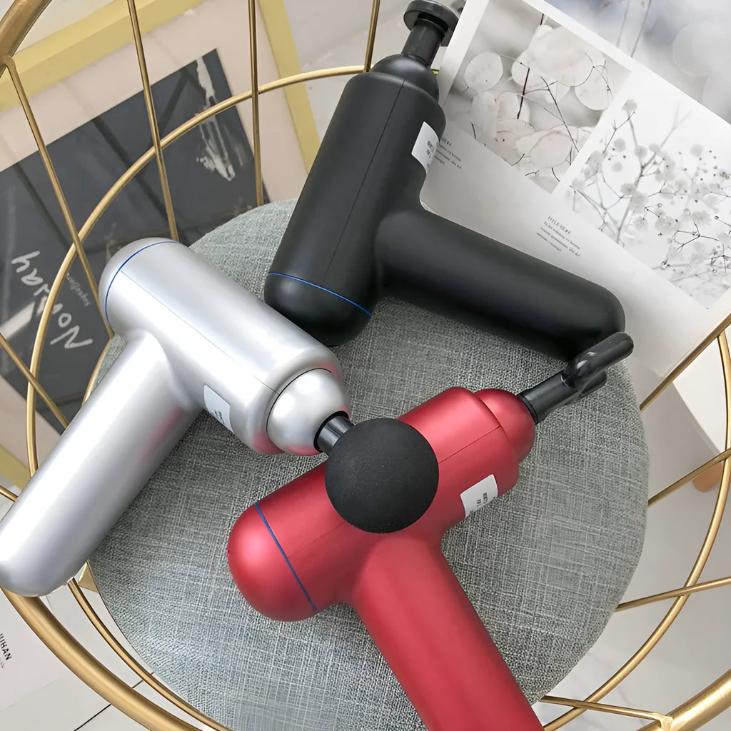 Black handheld electric fascia gun muscle massager with metal head on a grey background.