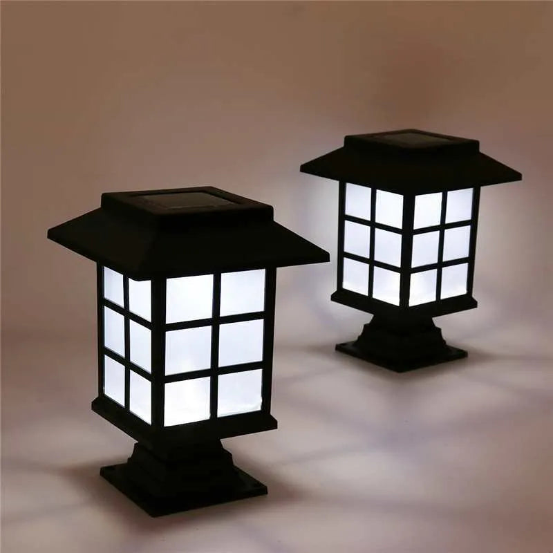 Solar outdoor LED lawn light with black body and white light through windows, set in a garden flower bed