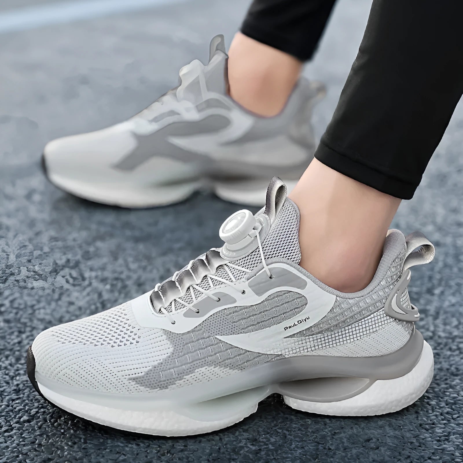 Men's white low-top running shoe with a rotating silver buckle on a grey background.