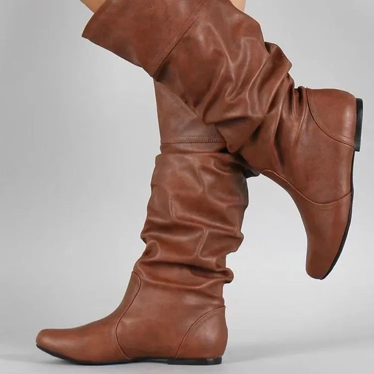 Women's black slip-on flat ankle boots with round toe and high shaft on a neutral background.