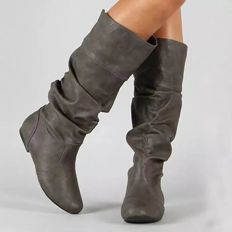 Women's black slip-on flat ankle boots with round toe and high shaft on a neutral background.