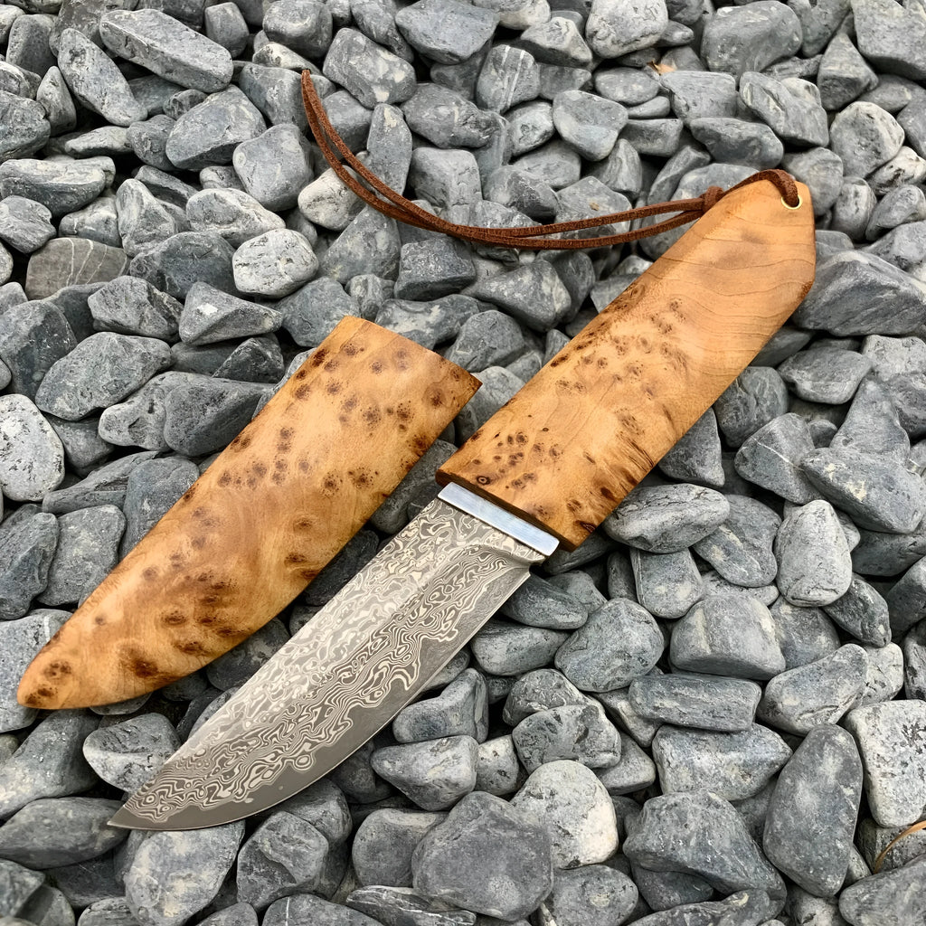 Damascus pattern steel short knife with VG10 steel blade and Thuja wood handle on wooden surface