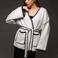 Loose knit camel coloured cardigan sweater with long sleeves on a hanger