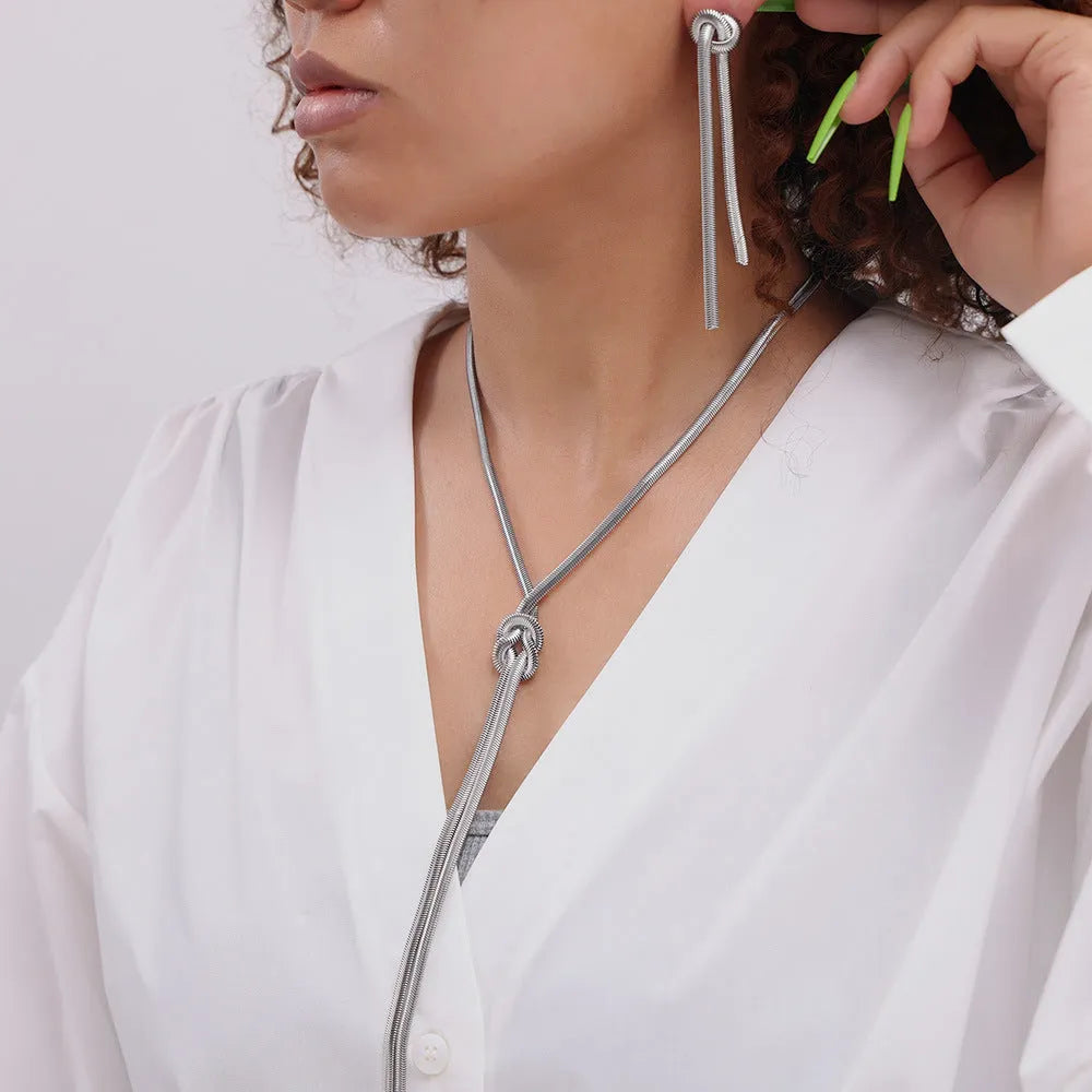 Gold knotted tassel snake chain long necklace with matching earrings on white background