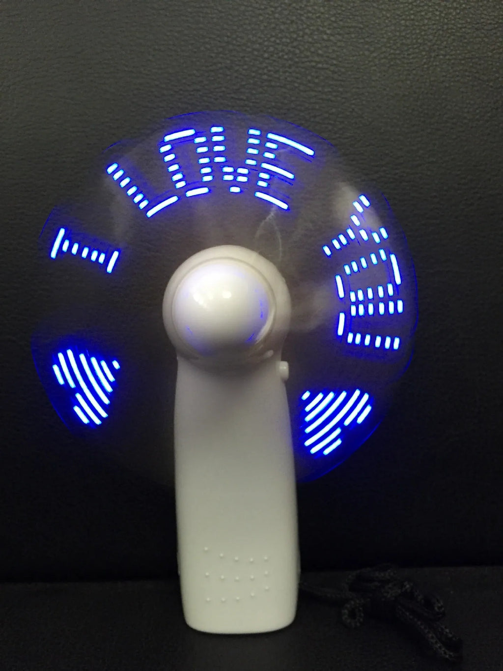 White handheld mini fan displaying blue and red LED 'I love you' pattern, shown next to a ruler for scale.