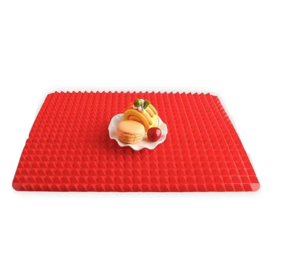 Red non-stick silicone pyramid cooking mat with grid on a baking tray for oven or BBQ use