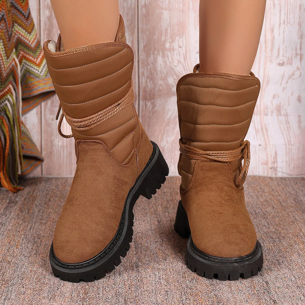 Women's black chunky heel snow boot with lace-up design and suede upper on a white background.