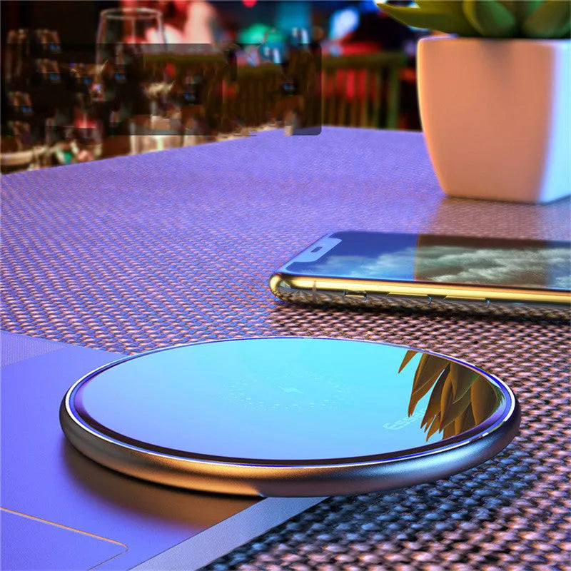 Black or white 15W Qi wireless charging pad on a table with LED light and phone charging.