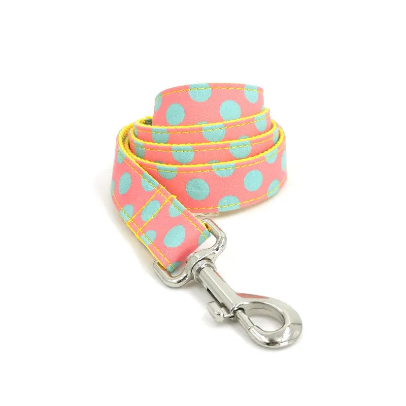 Yellow polka dot pet collar and matching hand-held traction rope lead set on plain background