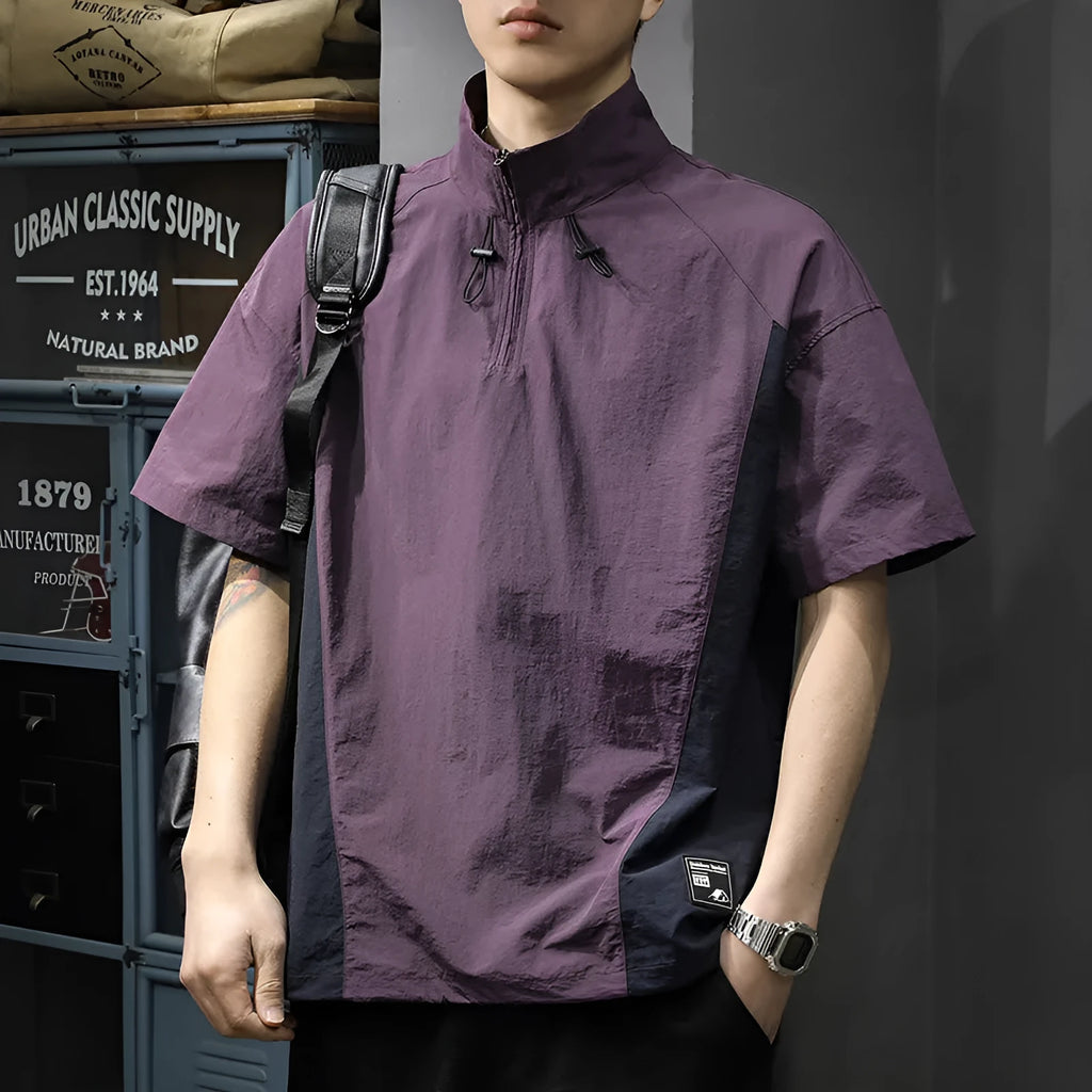 Man wearing a brown short-sleeved shirt with a half-zipped stand collar, showing the loose fit.