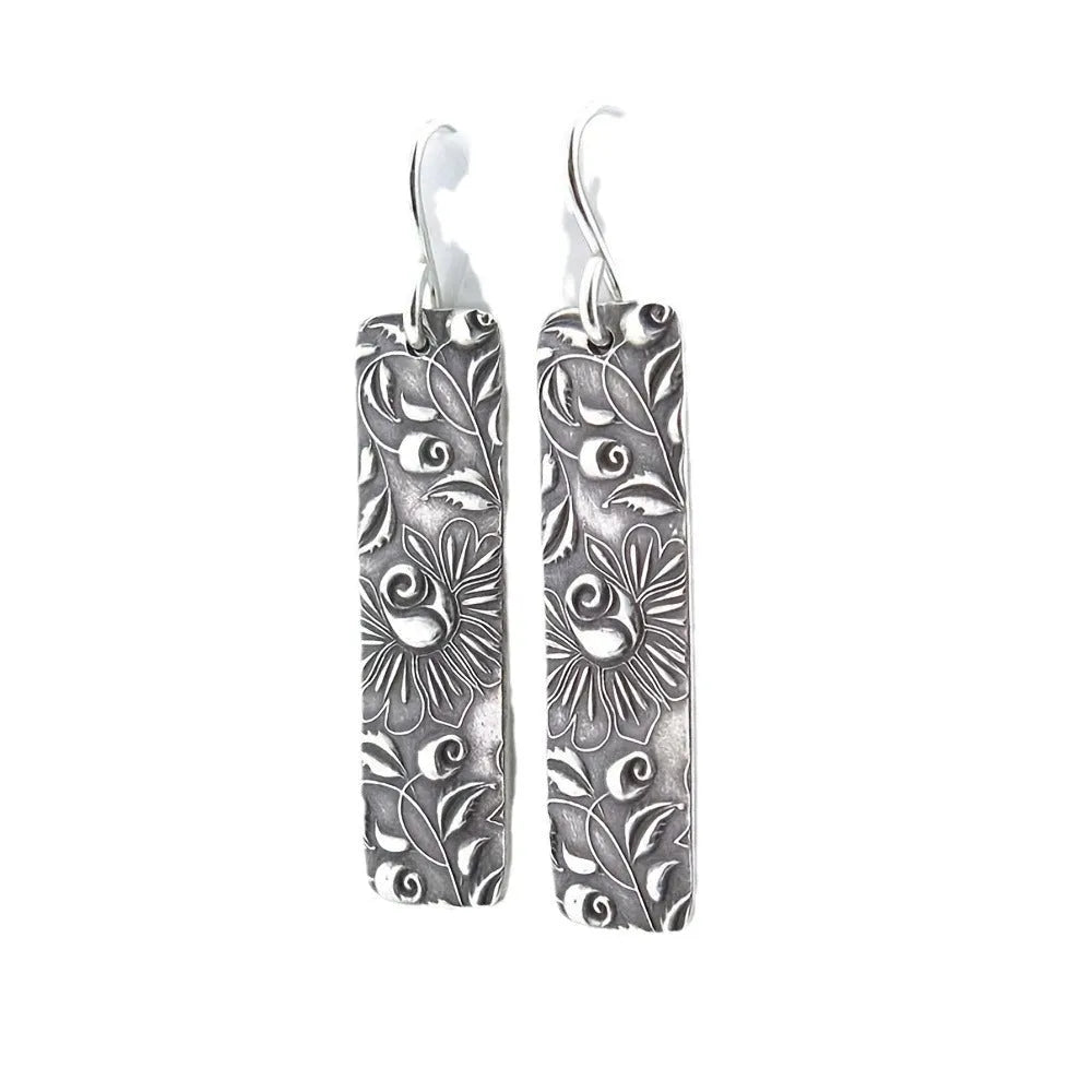Silver retro geometric long strip carved vine earrings made from zinc alloy on a plain background