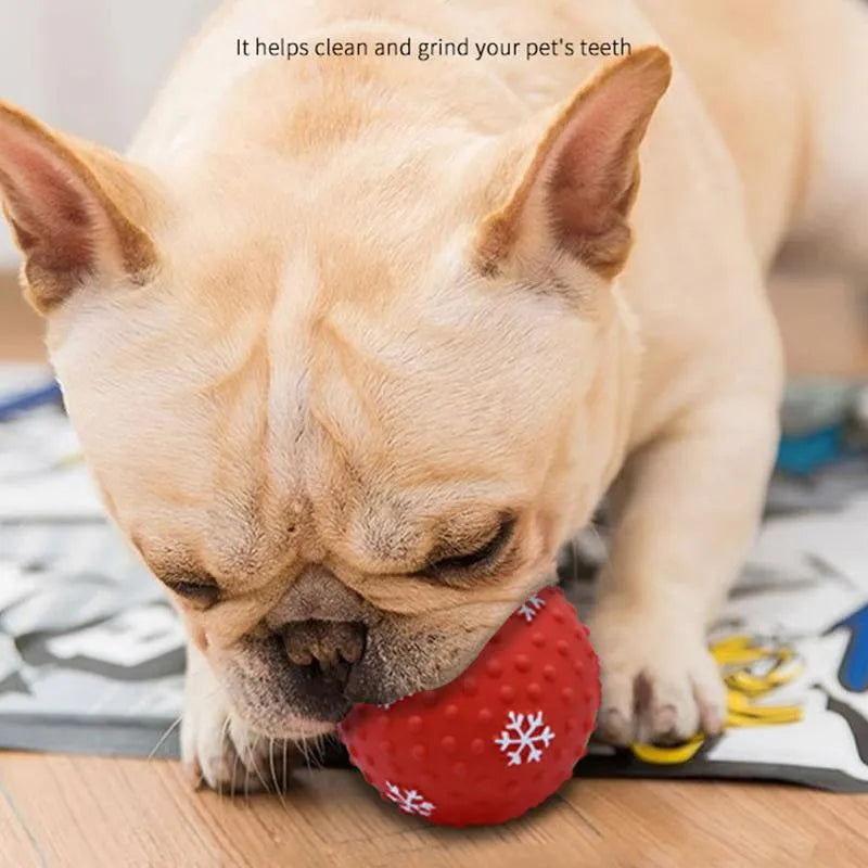 Red dog toy ball with snowflake print pattern, 7cm diameter, bouncing on grass