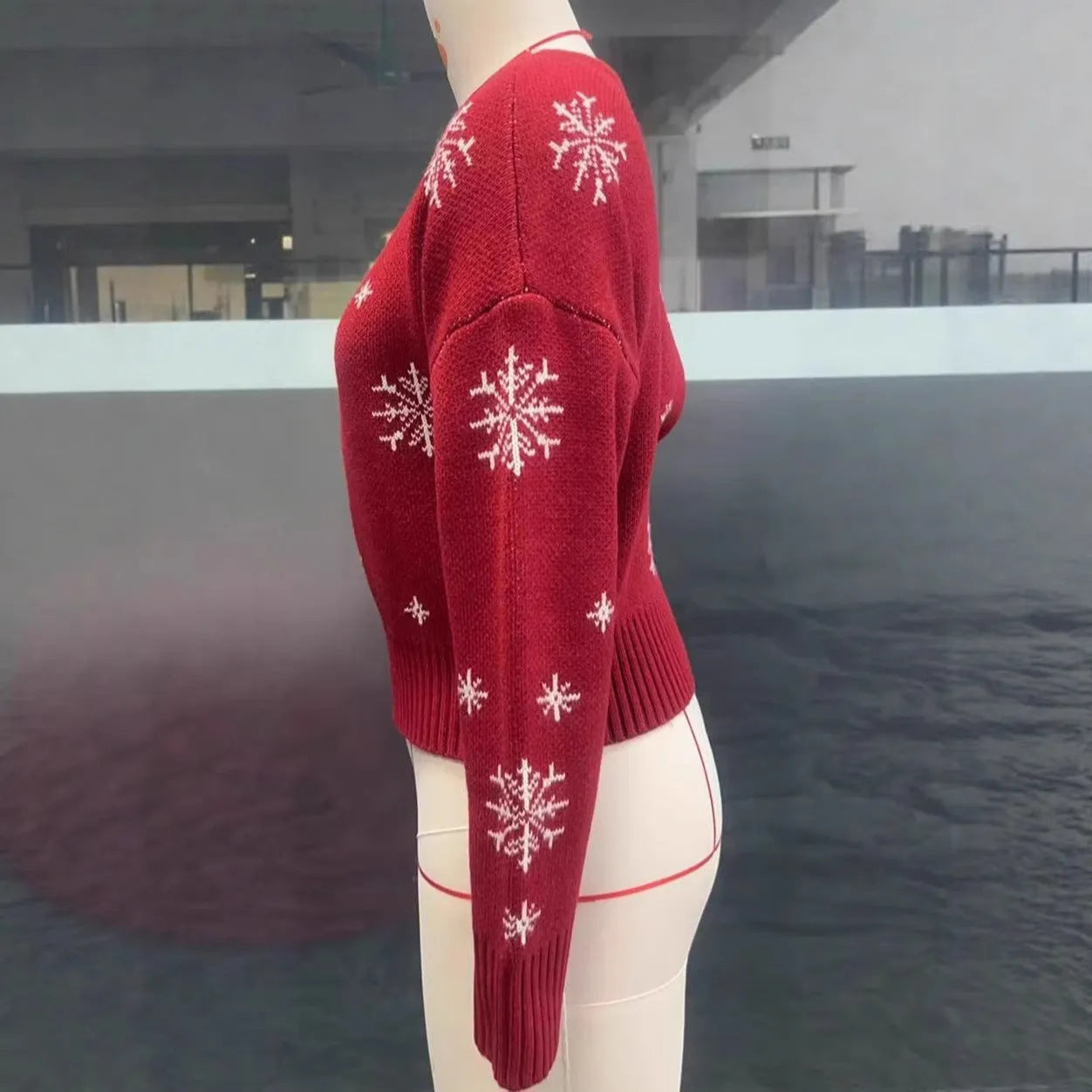 Women's red snowflake jacquard boat neck pullover sweater with long sleeves and crocheted flower details on a white background