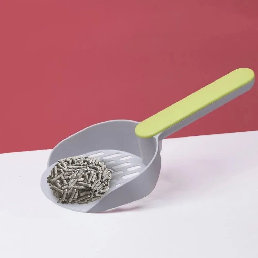Plastic cat litter shovel in blue, green, and pink colours on a clean surface