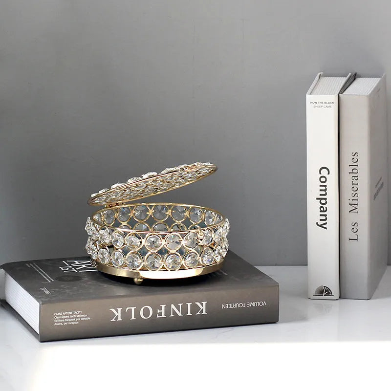 Clear crystal glass jewellery box with a French gold metal frame on a table.