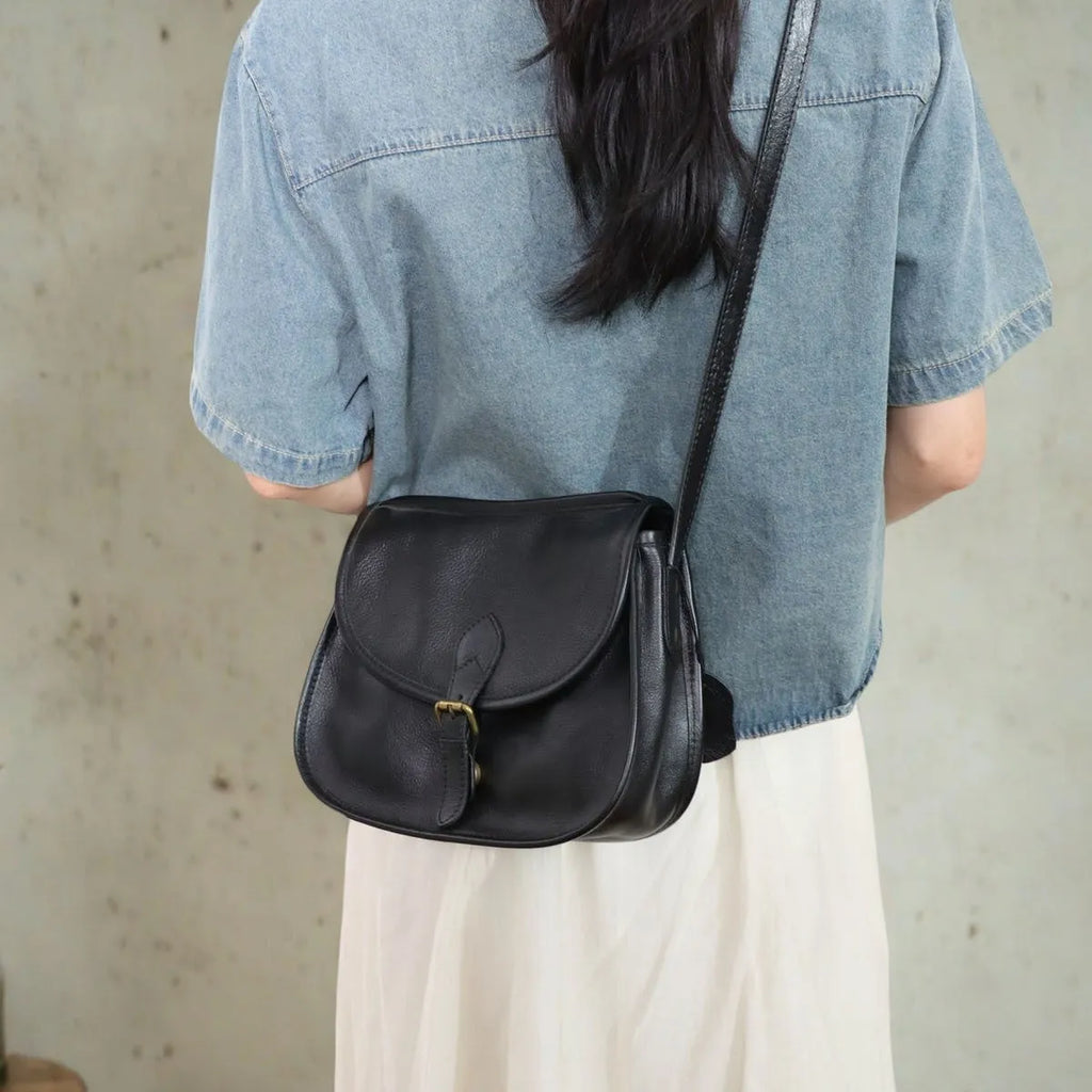 Genuine leather messenger bag in brown, soft shell shape with flap closure and visible sewing detail