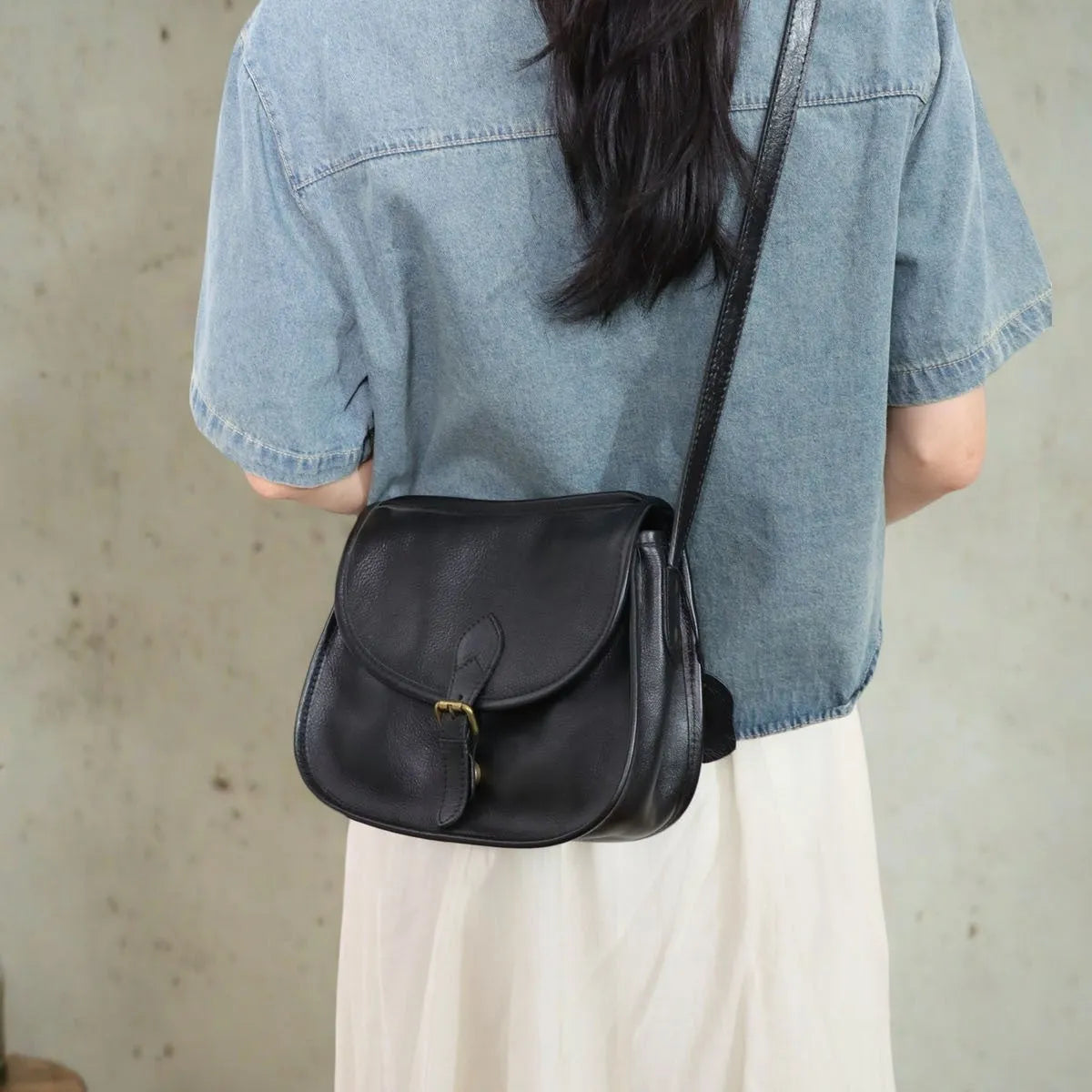 Genuine leather messenger bag in brown, soft shell shape with flap closure and visible sewing detail