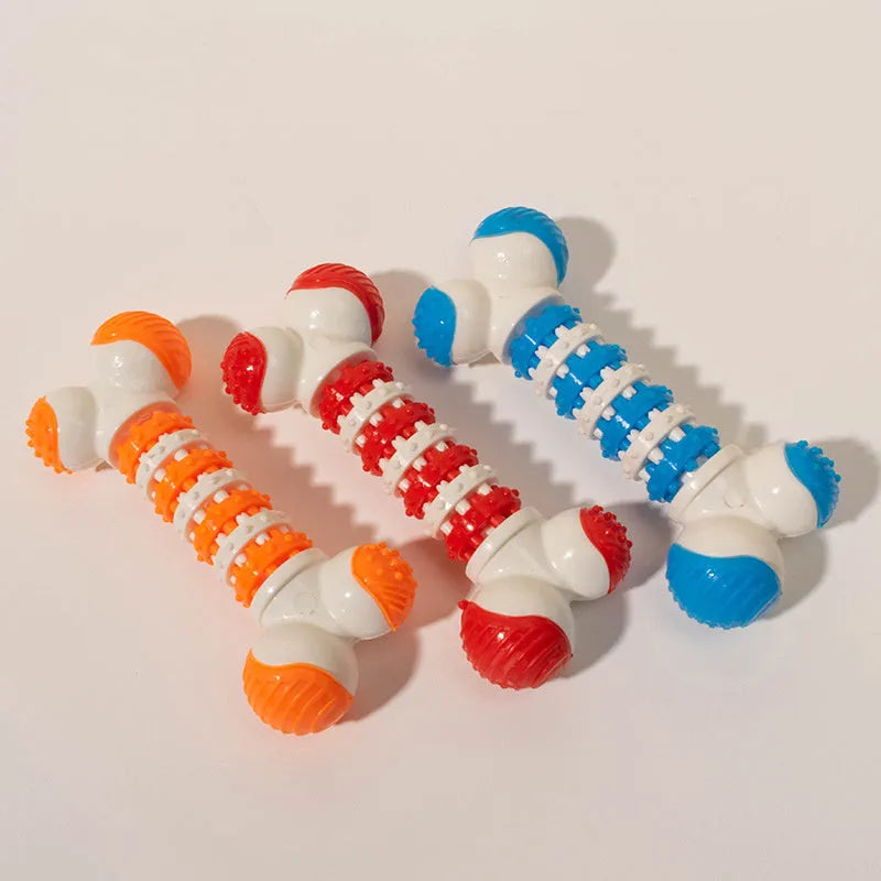 Blue, orange, and red bone-shaped rubber dog chew toy with a treat slot, shown next to dog biscuits.