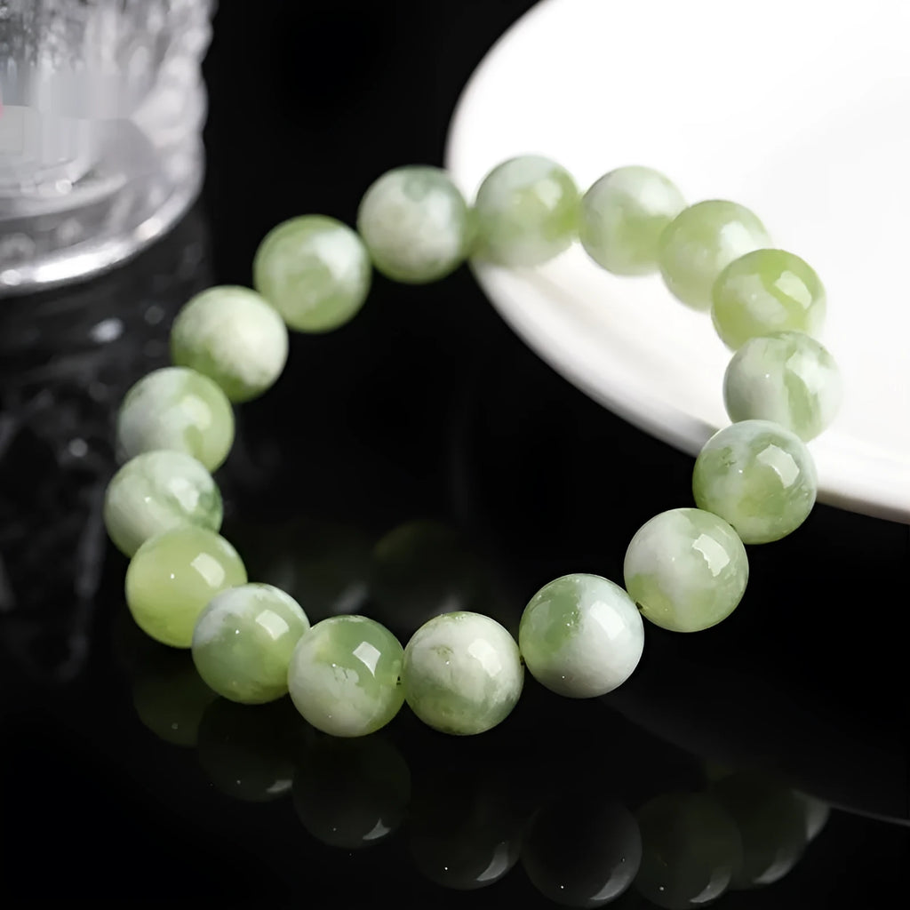 Green milk-in-water Xiuyan jade bracelet with polished geometric beads on white background
