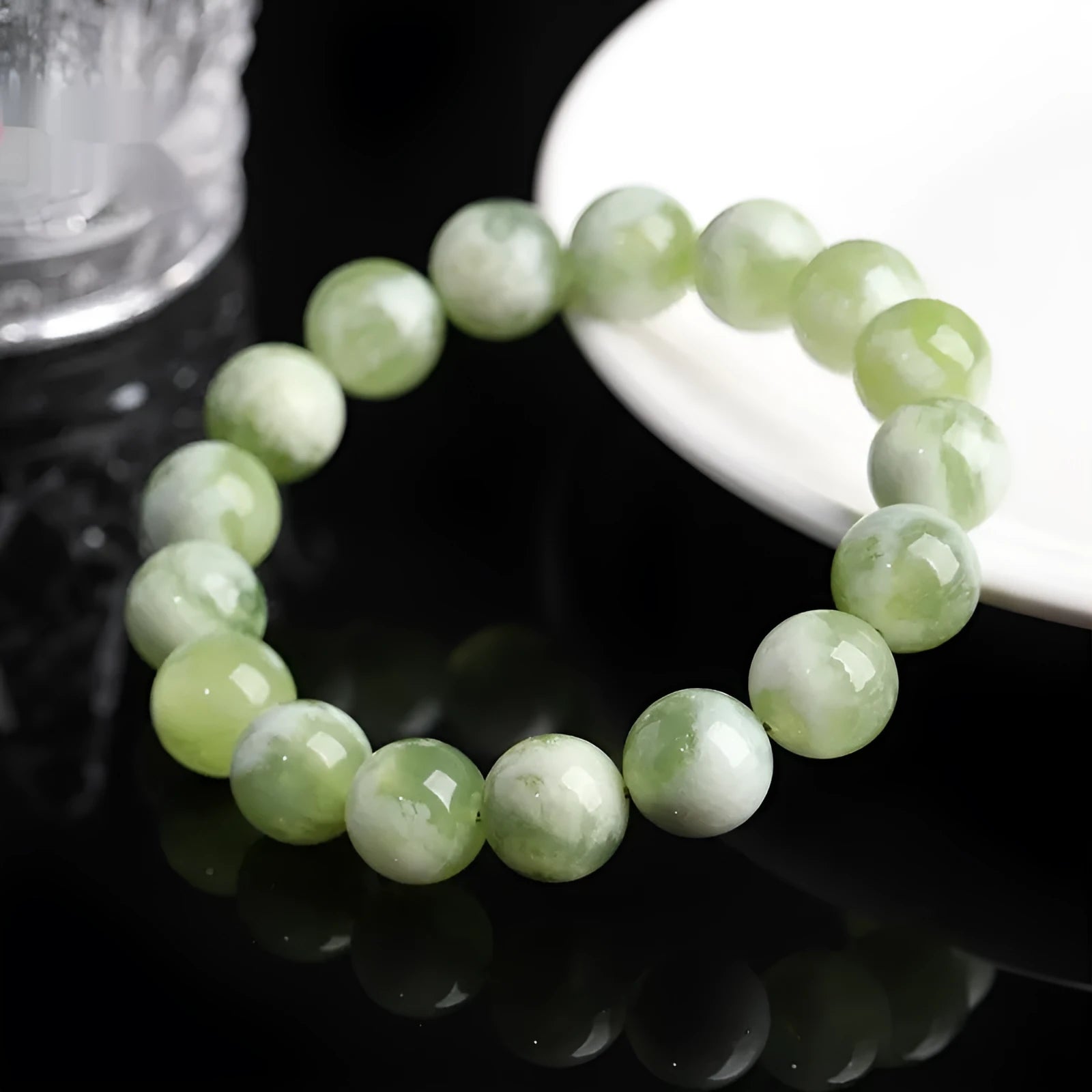 Green milk-in-water Xiuyan jade bracelet with polished geometric beads on white background