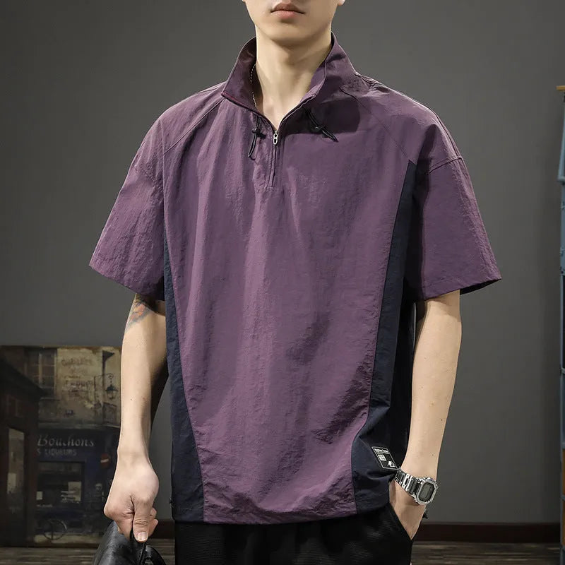 Man wearing a brown short-sleeved shirt with a half-zipped stand collar, showing the loose fit.