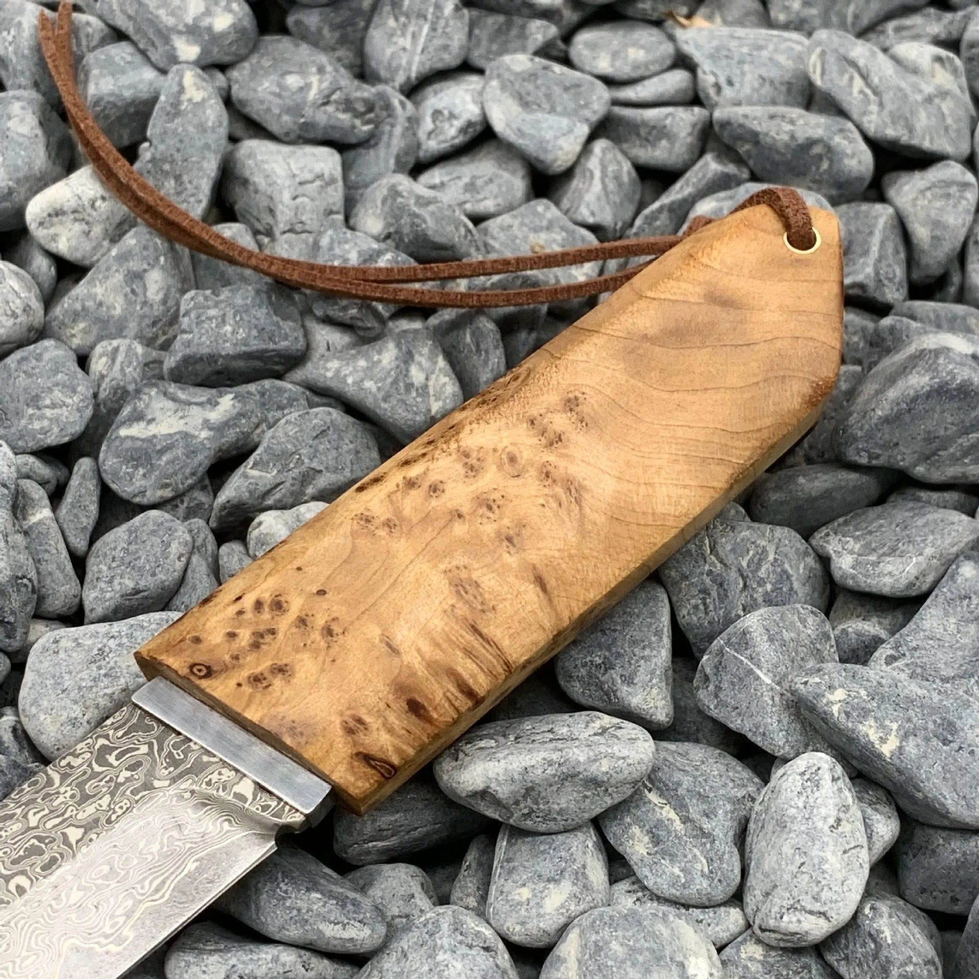 Damascus pattern steel short knife with VG10 steel blade and Thuja wood handle on wooden surface
