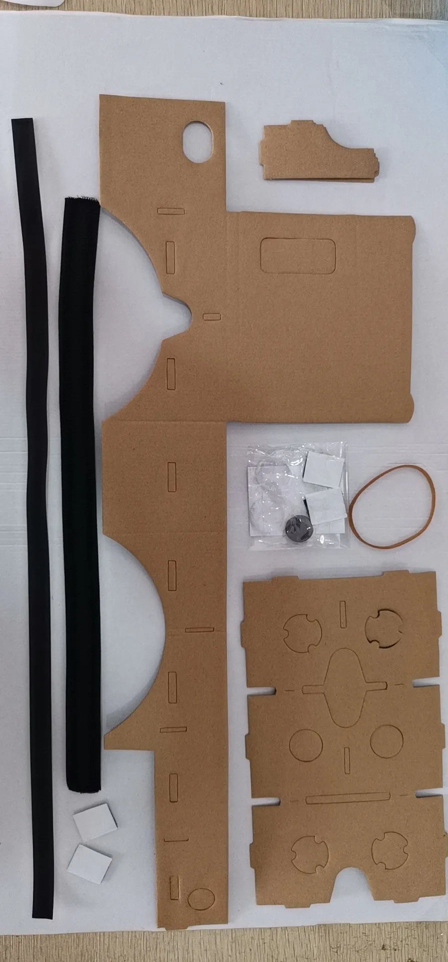 Pink and white cardboard VR headset for smartphones with adjustable straps and 3D lenses.