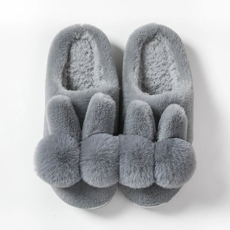 Women's fluffy rabbit fur high upper winter slippers in grey on a wooden floor.