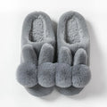 Women's fluffy rabbit fur high upper winter slippers in grey on a wooden floor.