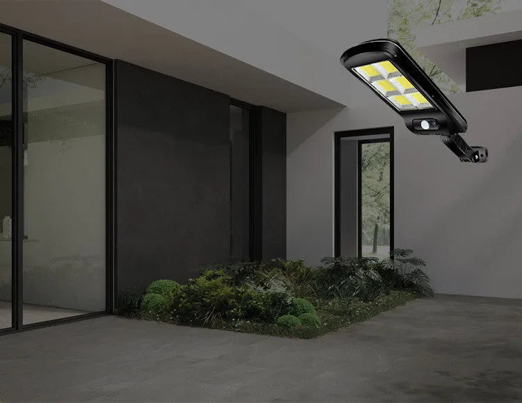 Black outdoor solar-powered motion sensor light mounted on a wall with solar panel visible.