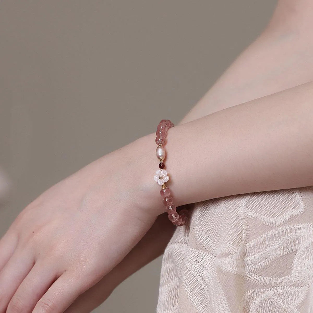 Women's strawberry quartz crystal bracelet with flower-shaped peach blossom design on wrist