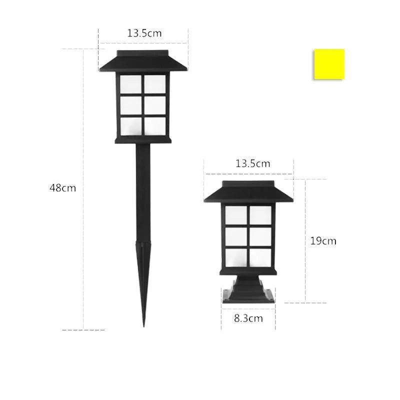 Solar outdoor LED lawn light with black body and white light through windows, set in a garden flower bed