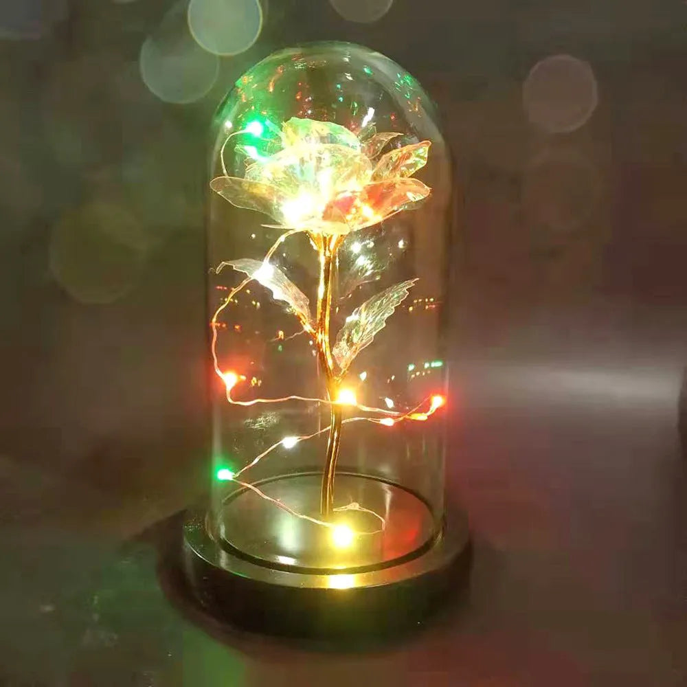Artificial gold rose in glass flask with LED lights on black base, 20cm tall