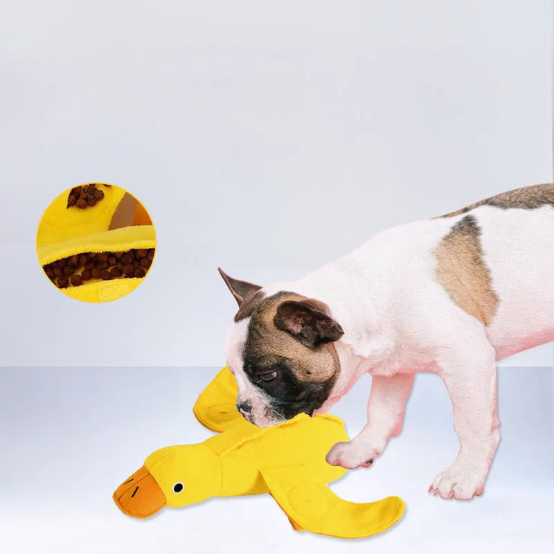 Yellow plush teddy dog toy with a attached duck doll and visible treat pockets on a white background.