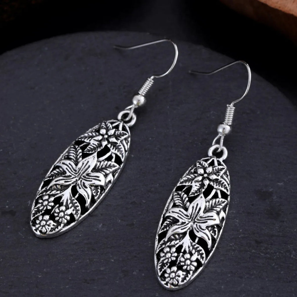 Pair of silver-tone retro hollowed out long water droplet drop earrings on light background