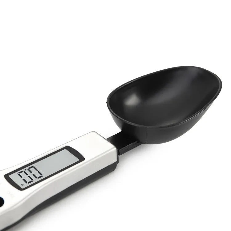 Digital smart measuring spoon with LCD display showing weight reading, on a kitchen countertop