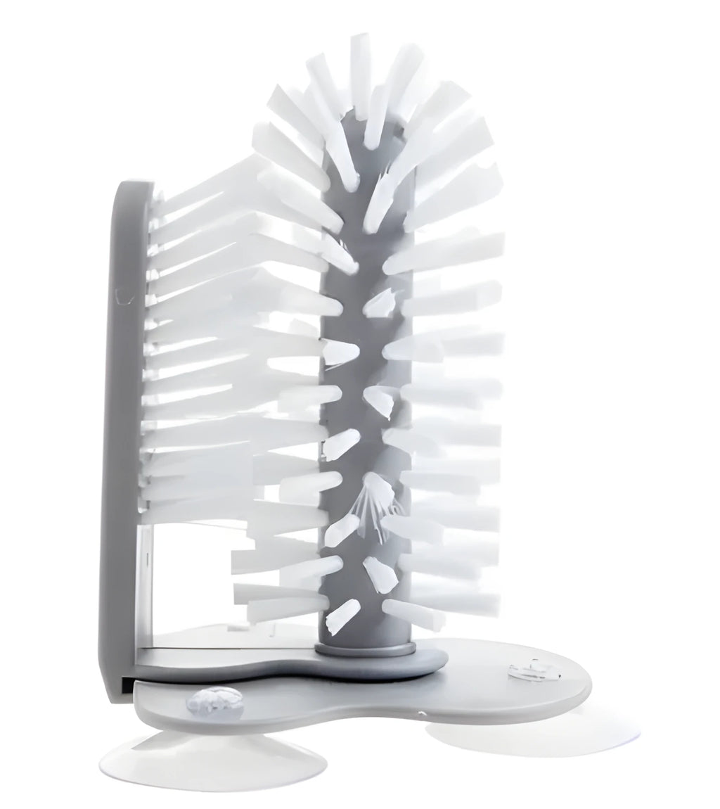 Grey suction cup brush with double-head design and two suction cups on a kitchen wall